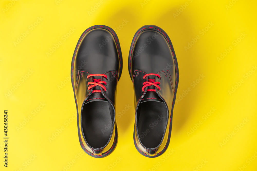 Stylish black leather shoes on yellow background, flat lay, top view