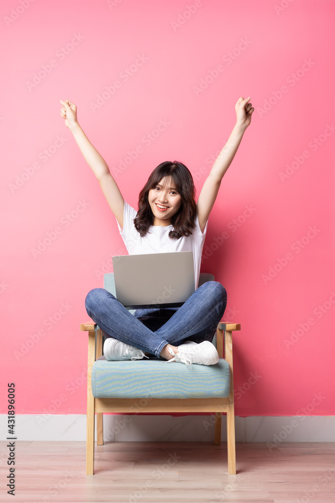 亚洲女人坐在沙发上用笔记本电脑，表情愉快