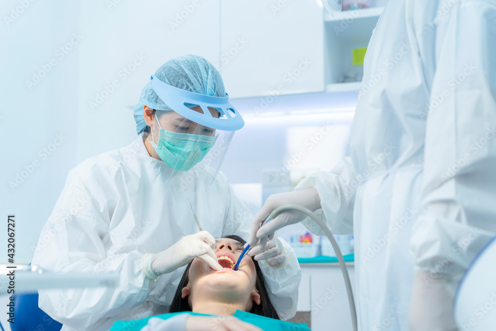 在牙科诊所提供口腔治疗的亚洲牙医和助理。