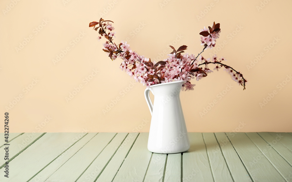 彩色木质背景上有美丽的开花树枝的花瓶