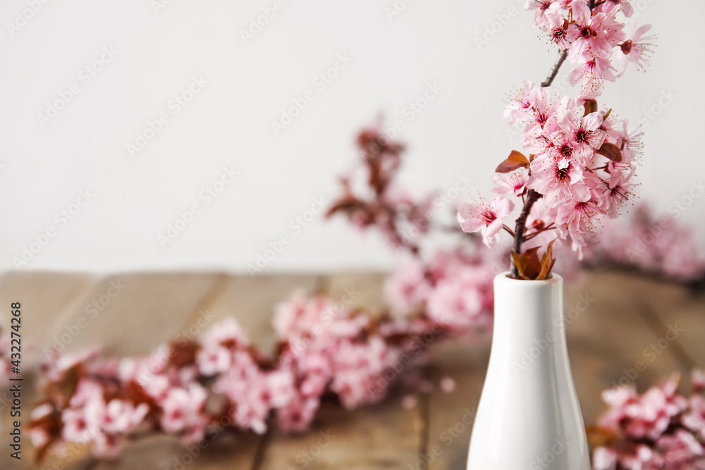 木桌上有美丽的开花树枝的花瓶