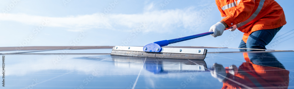 技术人员或操作人员在发电时使用拖把清洁太阳能电池板的选择性聚焦拖把