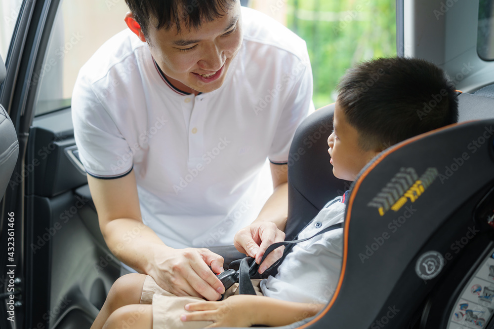 亚洲父亲在旅行时点击孩子进入汽车座椅，父亲与孩子互动