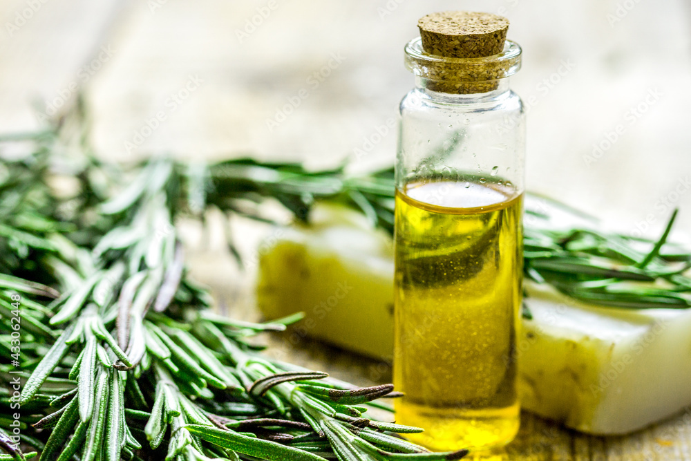 cosmetic oil in bottle and soap with herbs on light table background