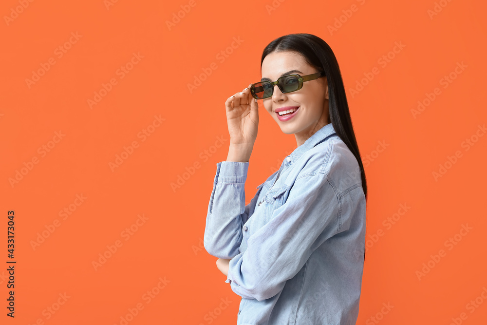 美丽的年轻女子戴着时尚的太阳镜，背景是彩色