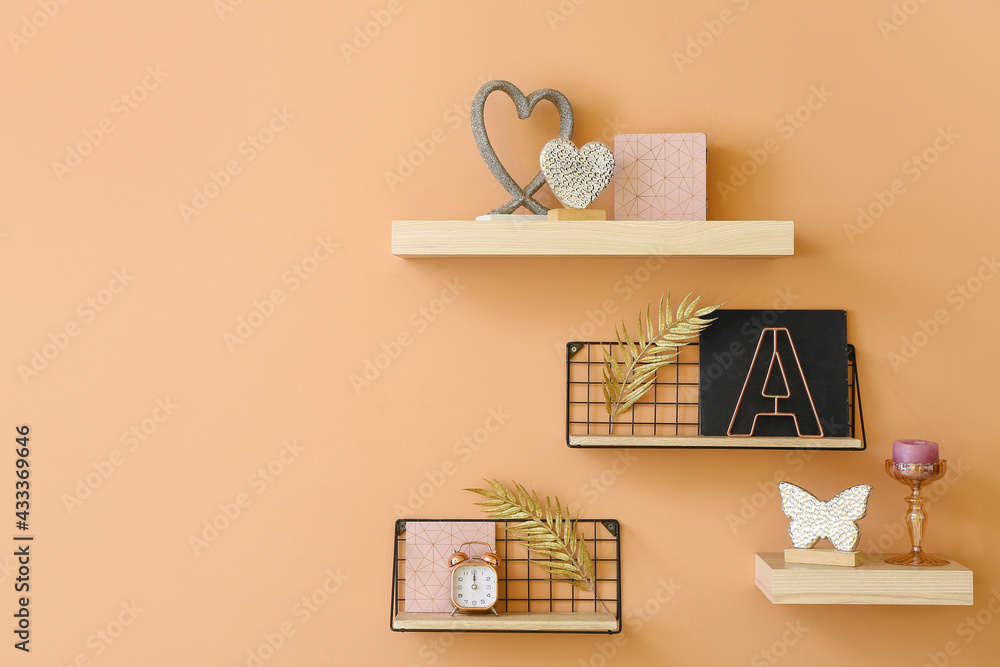 Shelves with alarm clock and decor hanging on color wall