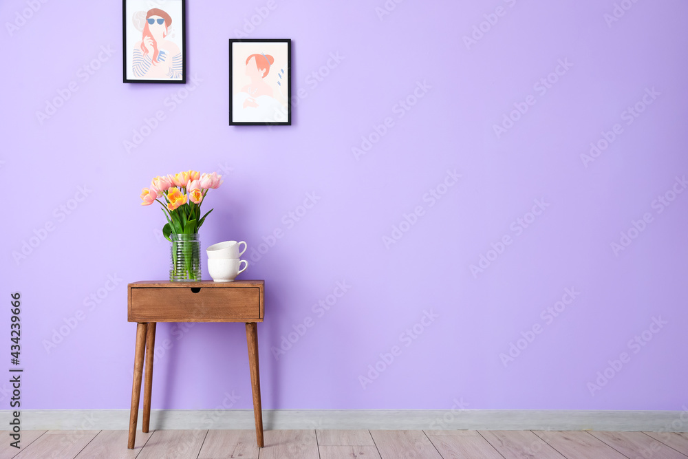 彩色墙附近木桌上的郁金香花束