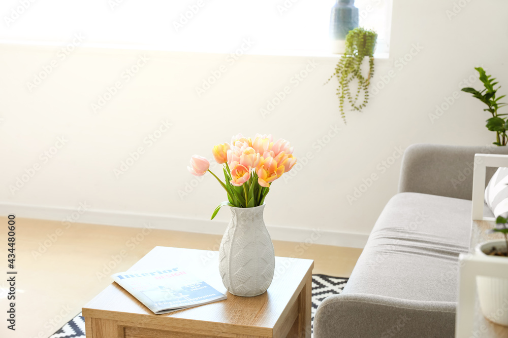 房间木桌上的郁金香花和杂志