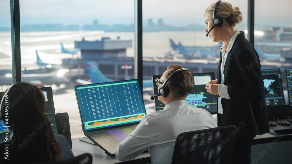 Female and Male Air Traffic Controllers with Headsets Talk in Airport Tower. Office Room is Full of 