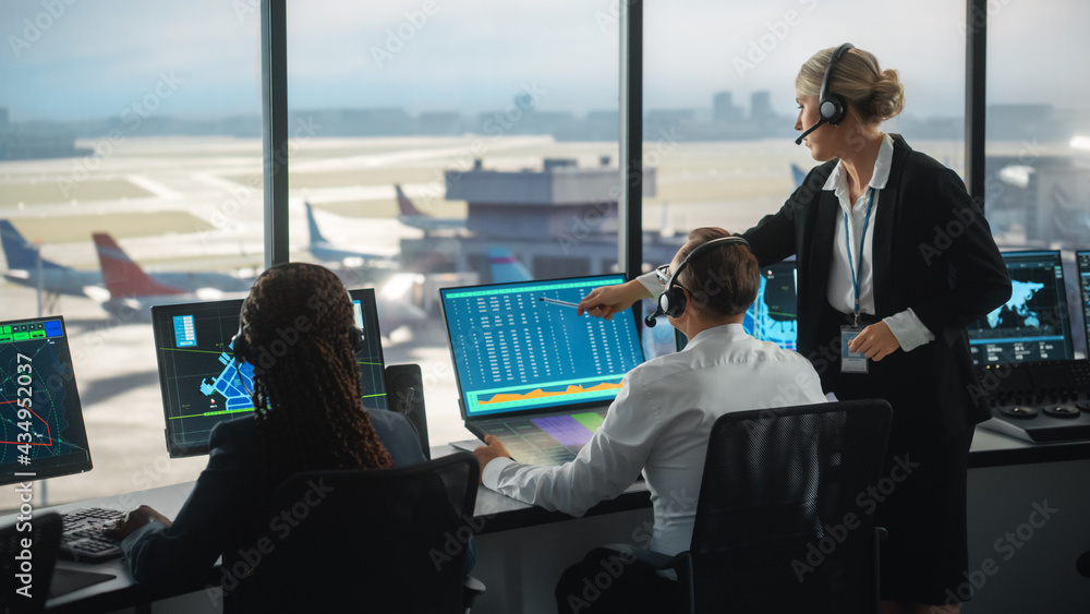 戴耳机的男女空中交通管制员在机场塔台交谈。办公室里挤满了人