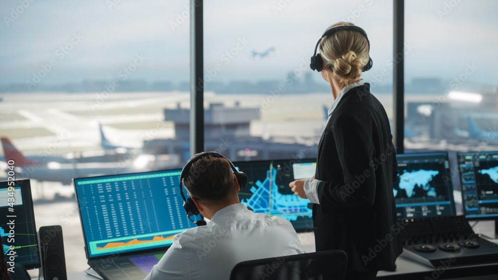 带耳机的男女空中交通管制员在机场塔台交谈。办公室里挤满了人