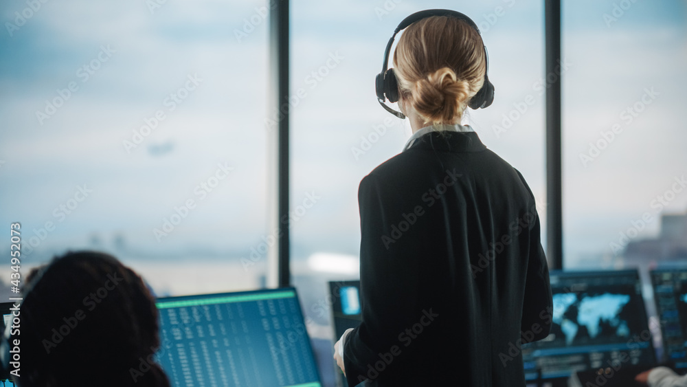 女空中交通管制员在机场塔台戴耳机通话。办公室里挤满了D