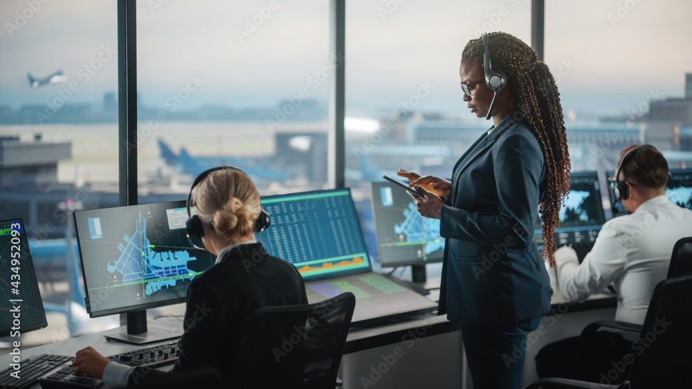 机场塔台黑人女空中交通管制员拿着平板电脑。办公室里摆满了桌面