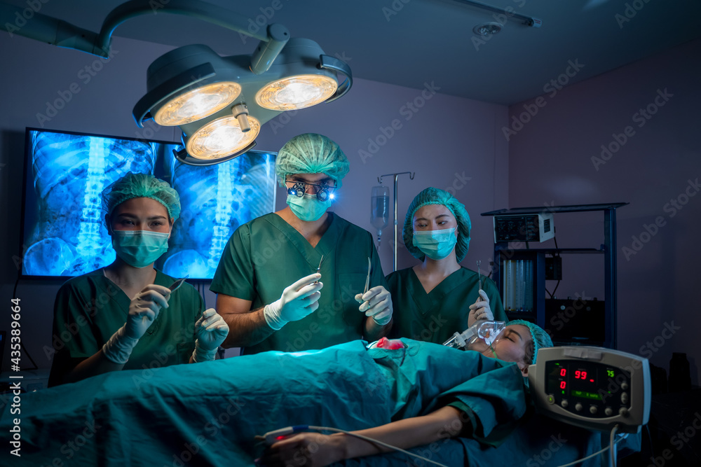 Group of surgeons working and examining the operation in operating room with surgery equipment.