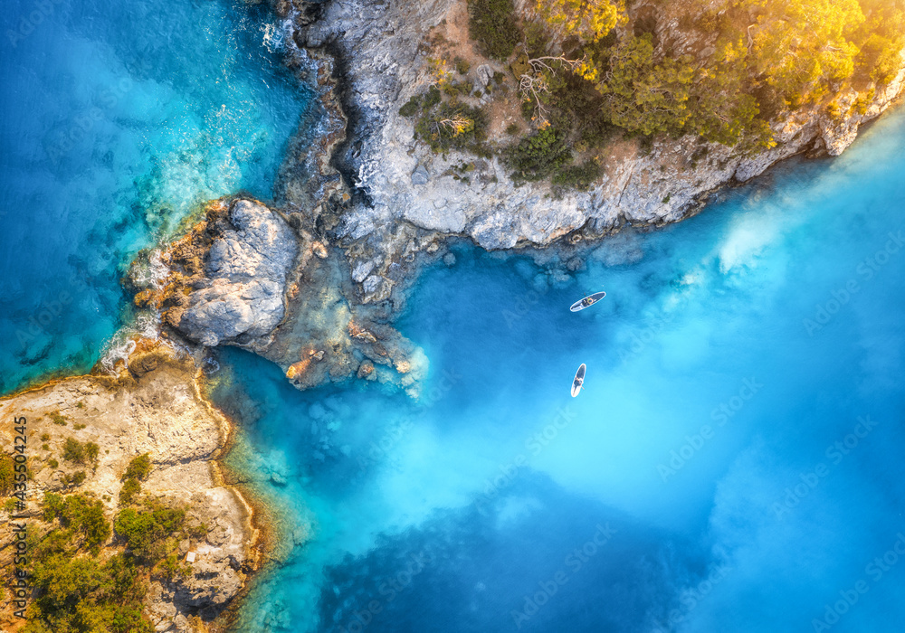 蓝色海洋中漂浮的木板和人的鸟瞰图，蓝色l中夏季日落时岩石和树木