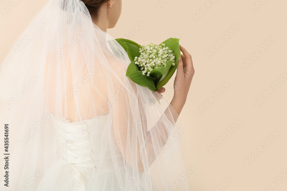 Bride with bouquet of beautiful lily-of-the-valley flowers on light background