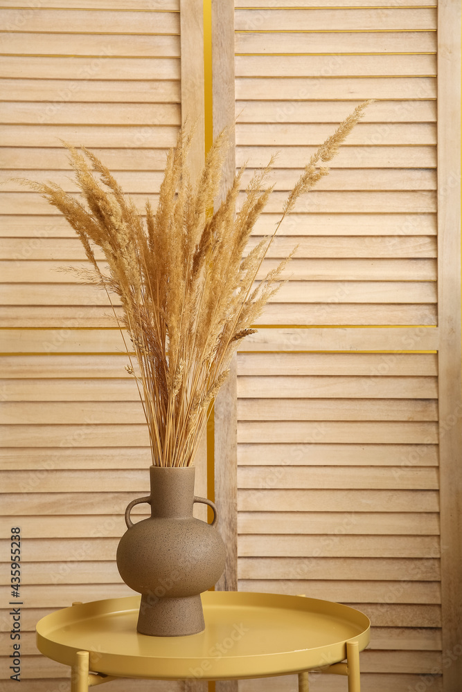 折叠屏风附近桌子上的小麦小穗花瓶