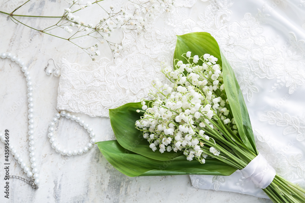 Beautiful lily-of-the-valley flowers and jewelry on light background