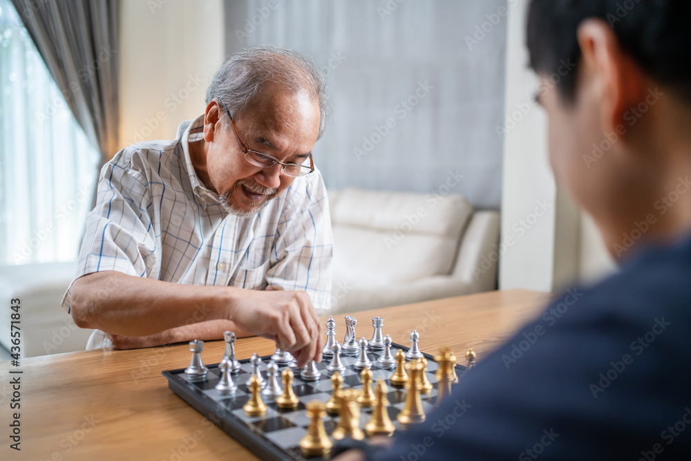 Happy Senior Elderly old man enjoy play chess game with friend at home