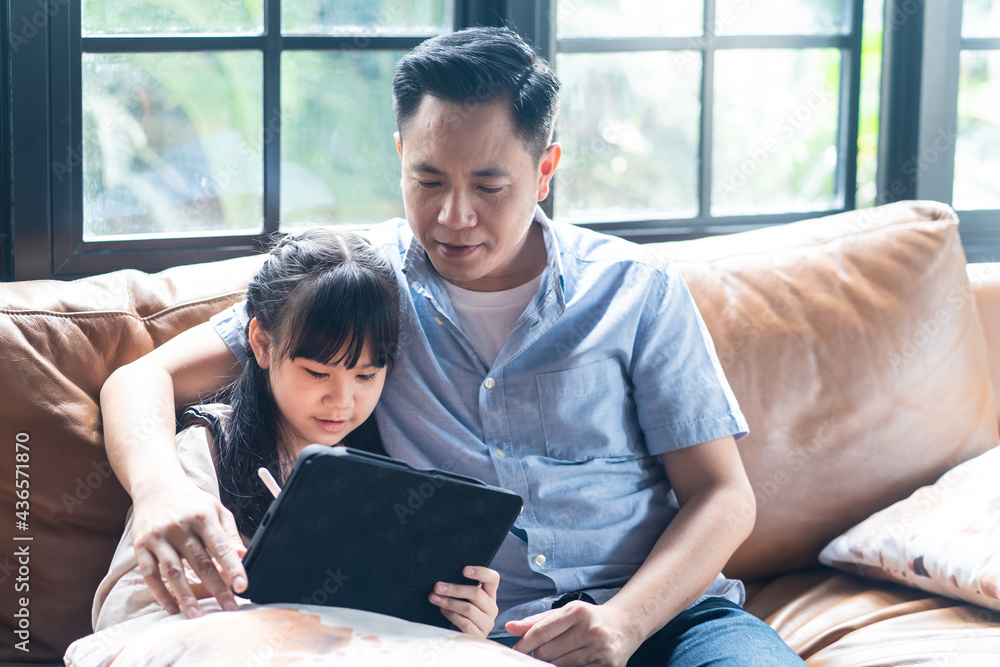 Father with daughter play game and study online on tablet together.