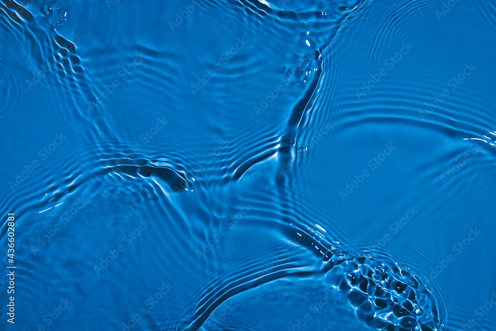 De-focused transparent dark blue colored clear calm water surface texture with splashes and bubbles.