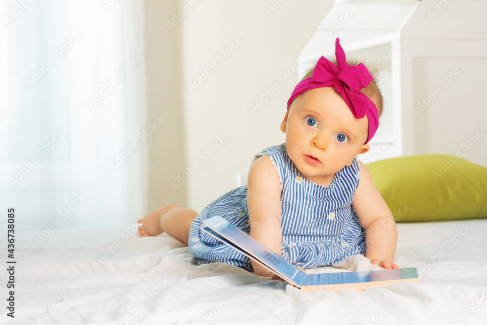 小时尚女婴在床上翻阅书本