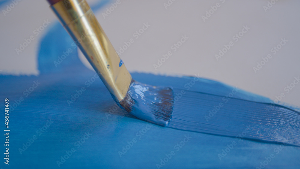 特写：画家用细画笔用油漆画出一条蓝色的线。