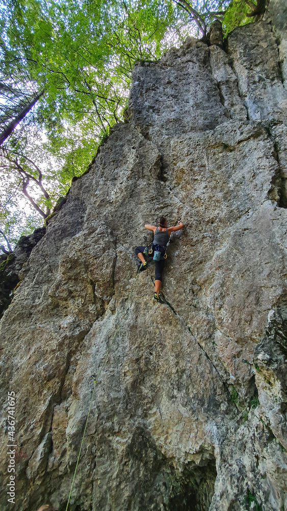 垂直：女性攀岩者用顶部绳索技术攀登陡峭的墙壁。