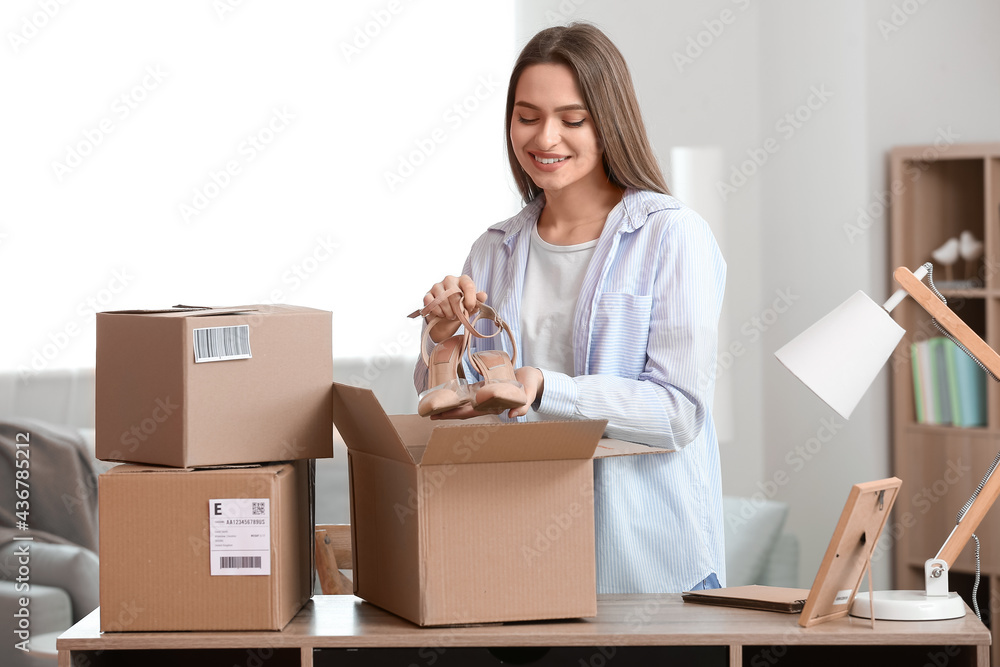 Young woman packing shoes for client at home