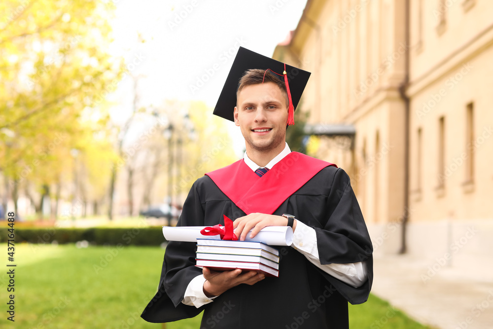 Male graduating student with books outdoors