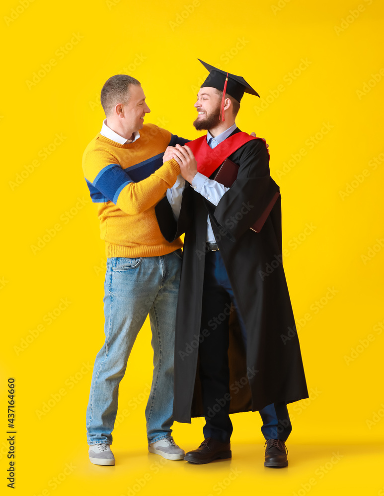 快乐的男毕业学生，有他的父亲在彩色背景下