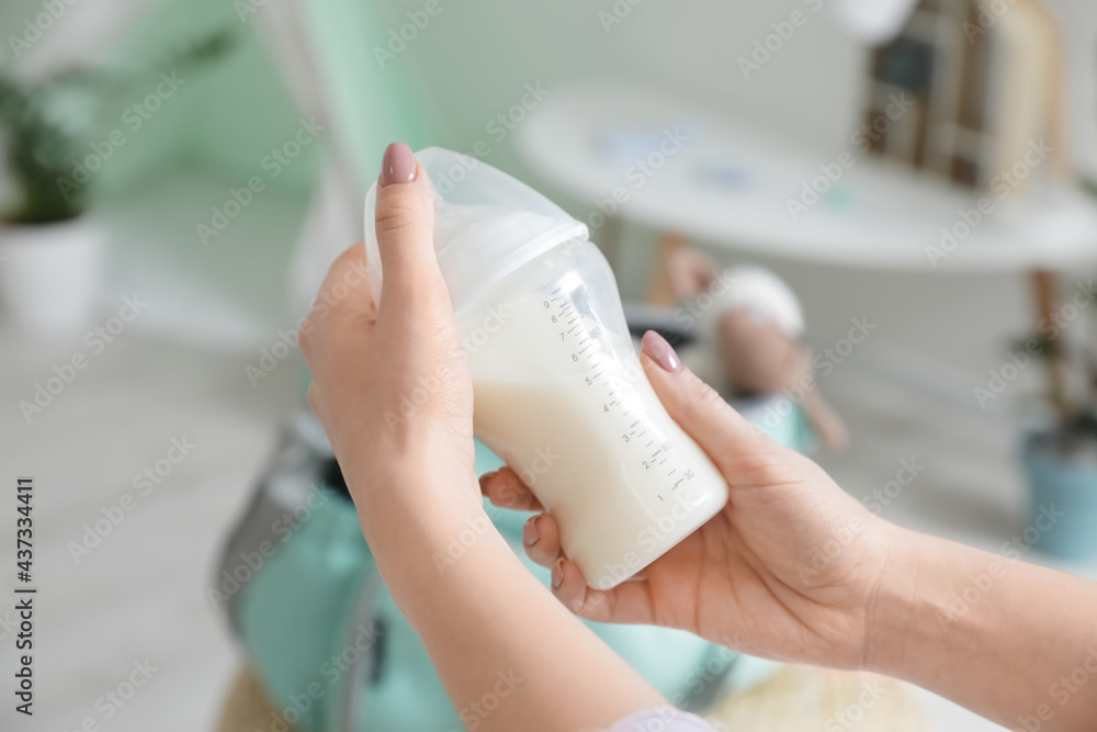 妇女拿着一瓶牛奶给婴儿，特写镜头