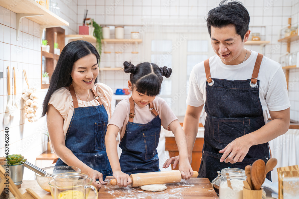 厨房里的幸福家庭父母教孩子在家里烤面包和食物