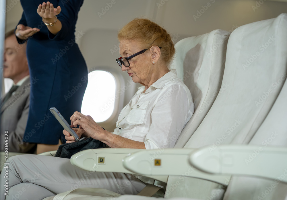 商务飞机上的乘客老年妇女在飞行中坐在座位上，旅行概念。