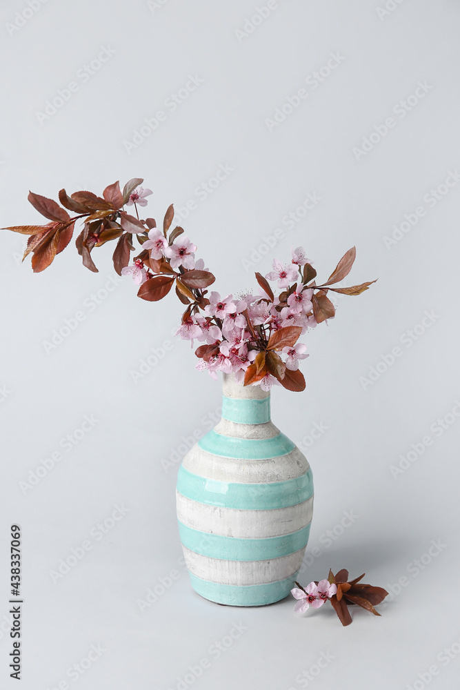 灰色背景上有美丽的开花树枝的花瓶