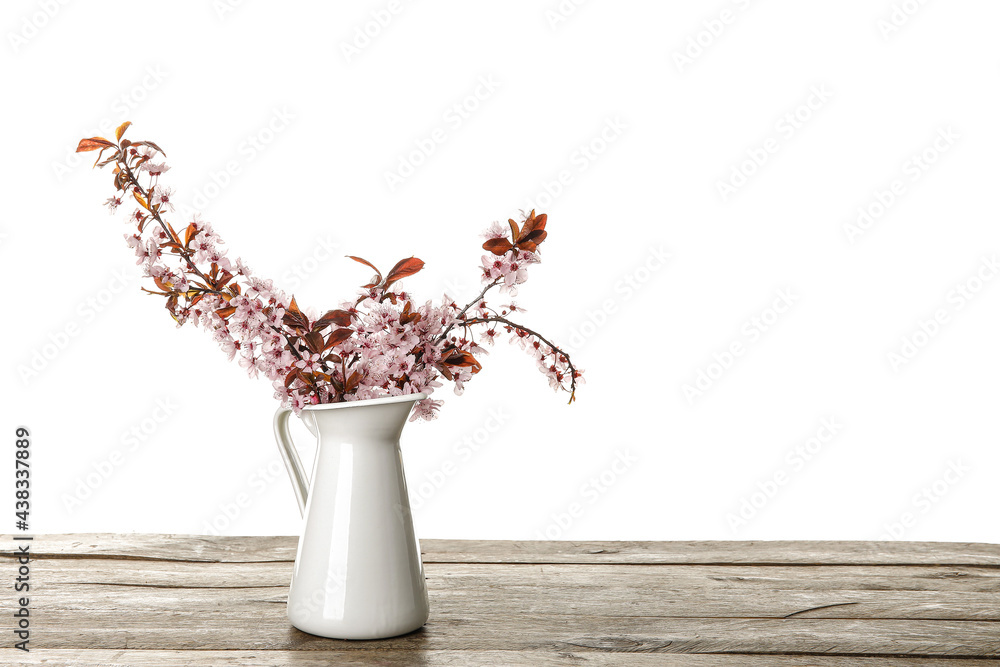 白色背景下，木桌上有美丽的开花树枝的罐子