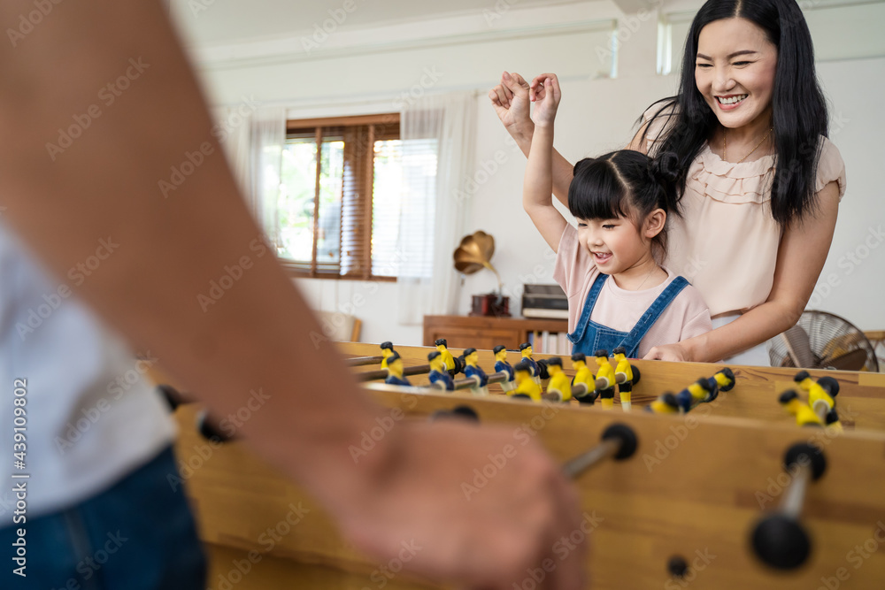 Young girl kid daughter have fun play table soccer with parent at home	
