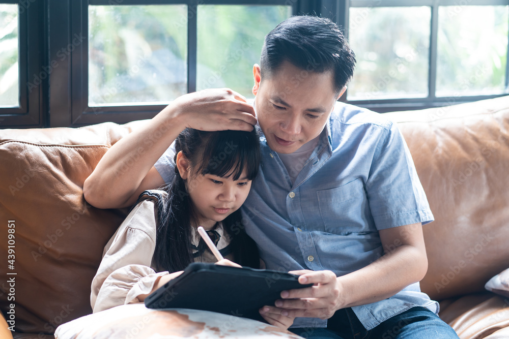 亚洲年轻父亲为女儿上电子学习课。