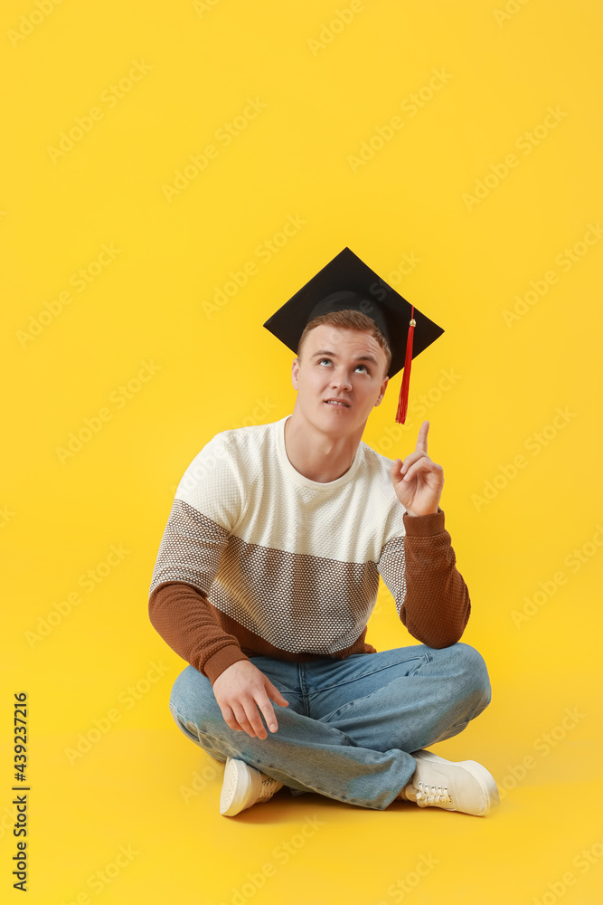男毕业生指着彩色背景上的东西