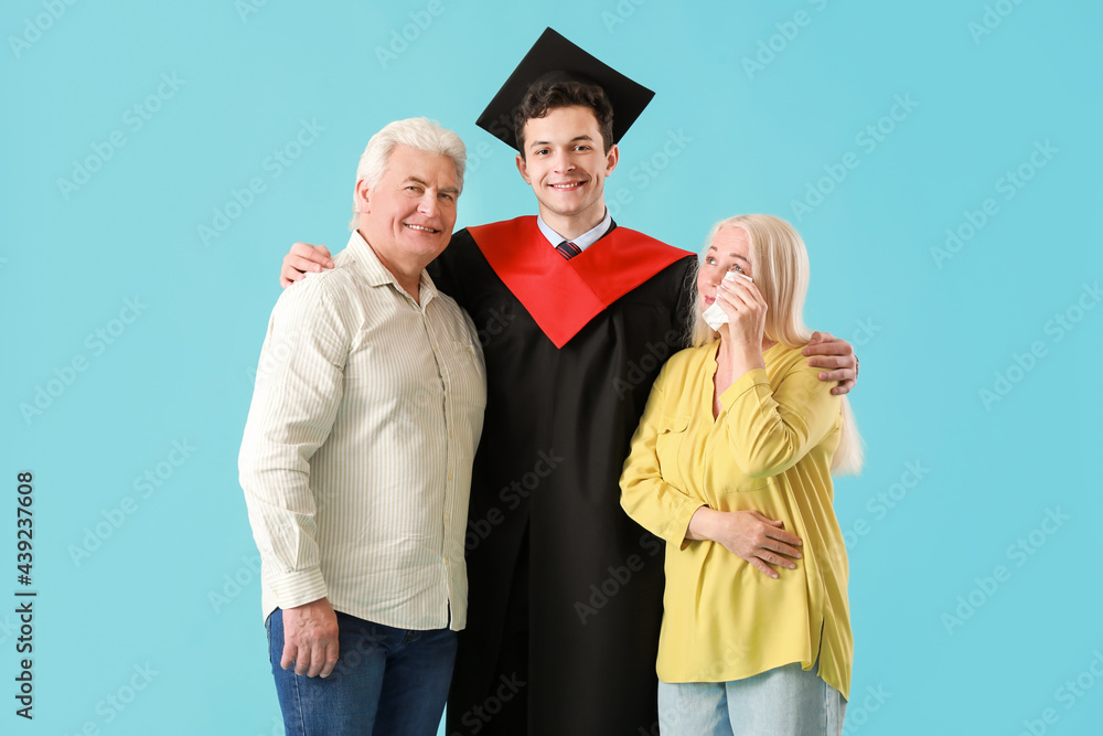 Happy male graduation student with his parents on color background