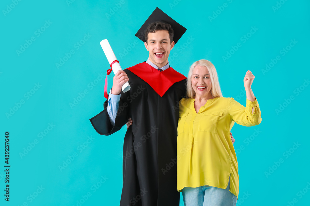 快乐的男毕业学生和他的母亲在彩色背景上