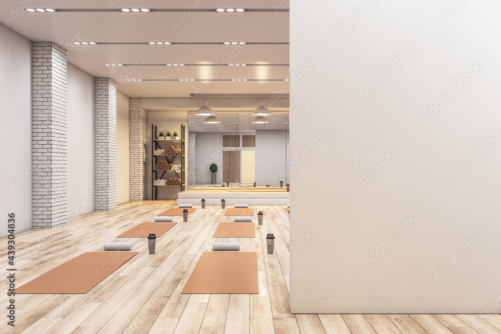 明亮的混凝土瑜伽馆内部，配有设备，墙上有空白的实体模型空间，日光和木制fl