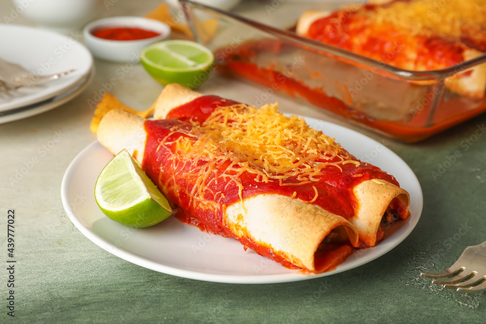 Plate with tasty cooked enchilada on color background