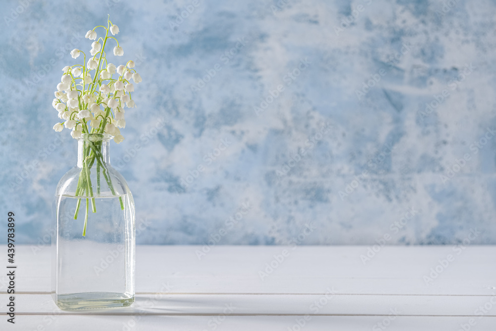Vase with beautiful lily-of-the-valley flowers on color background