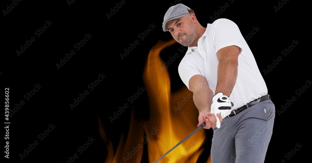 Caucasian male golf player swinging golf club against fire flame effect on black background