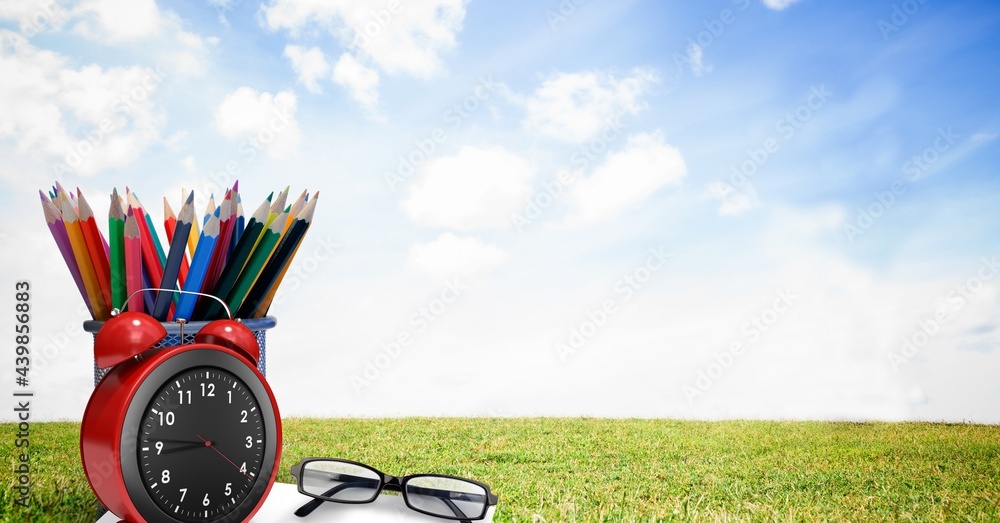 眼镜、闹钟和铅笔架，与草地和蓝天相映成趣