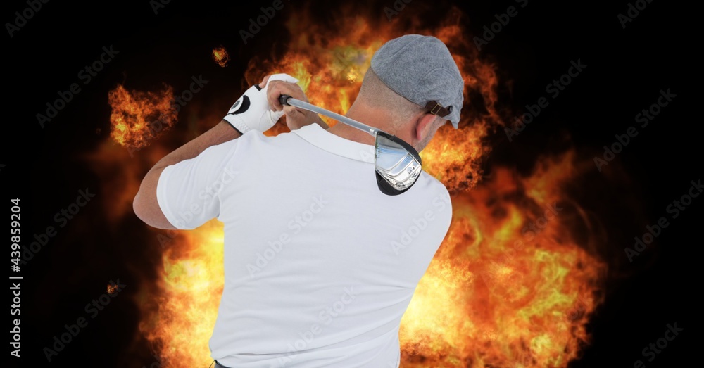 Rear view of senior male golf player swinging club against fire flame effect on black background