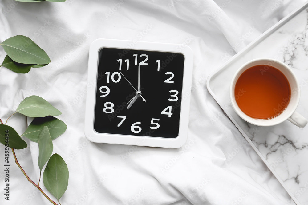 时尚的时钟和床上的一杯茶