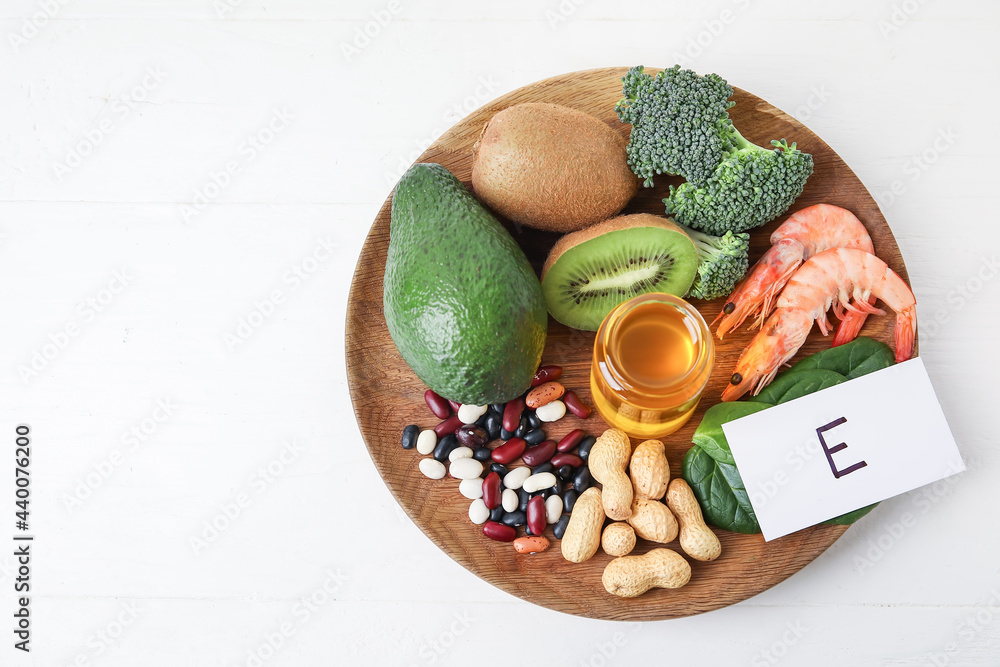 Plate with healthy products rich in vitamin E on white background