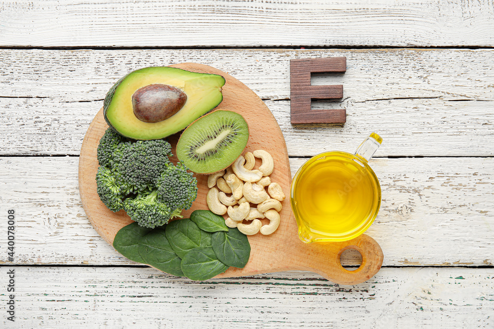 Board with healthy products rich in vitamin E on light wooden background